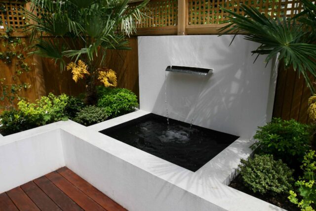 Decking design london elegant walled outdoor entertaining space Wimbledon South West London, lush planting, cozy relaxing outdoor dining area, water feature.
