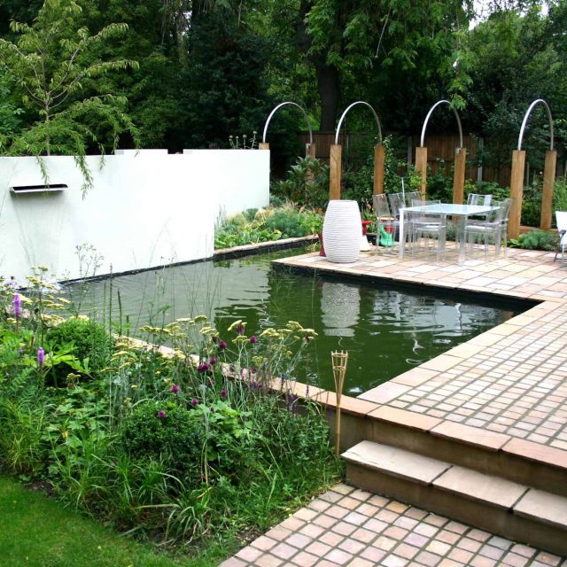 A reflective pond and water wall on a stone terrace in contemporary Dulwich.