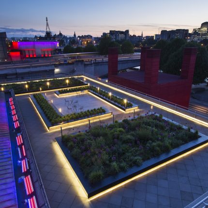 A modern London rooftop terrace with an LED planter featuring alliums and grasses.