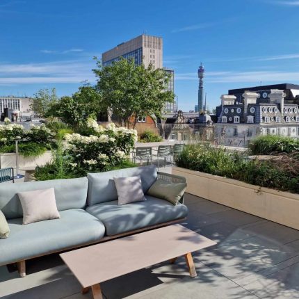 A modern London rooftop terrace with sofa seating and planters, overlooking the BT Tower.