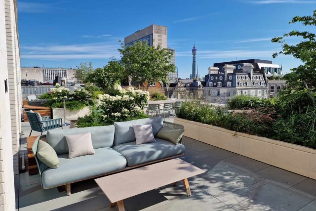 A modern London rooftop terrace with sofa seating and planters, overlooking the BT Tower.