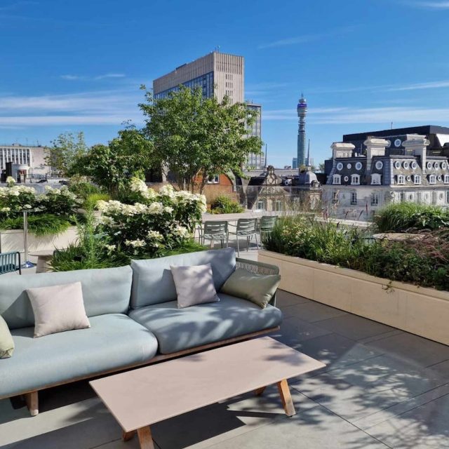 A modern London rooftop terrace with sofa seating and planters, overlooking the BT Tower.