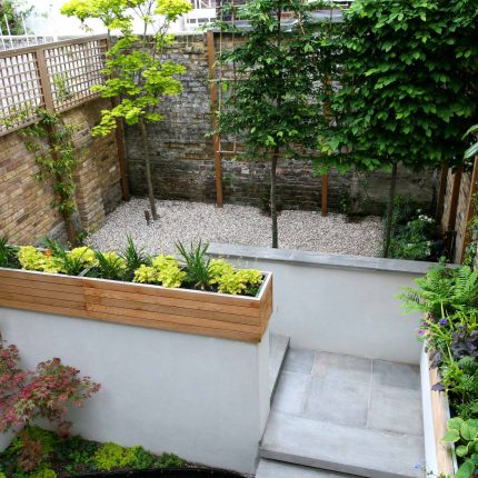 Gravel small town garden Chelsea with a beautiful water feature, acer planters landscaper designers with horizontal timber cladding by Edlis Design Associates.