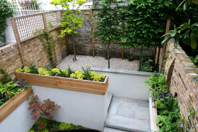 Gravel small town garden Chelsea with a beautiful water feature, acer planters landscaper designers with horizontal timber cladding by Edlis Design Associates.