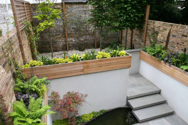 Gravel small town garden Chelsea with a beautiful water feature, acer planters landscaper designers with horizontal timber cladding by Edlis Design Associates.