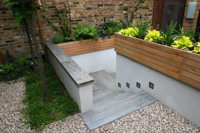 Gravel small town garden Chelsea with a beautiful water feature, acer planters landscaper designers with horizontal timber cladding by Edlis Design Associates.