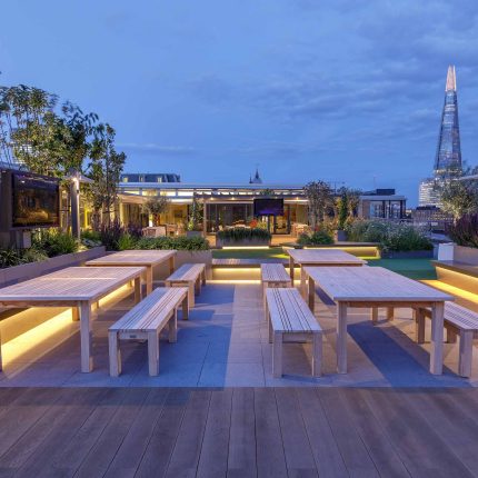 Large Central London commercial roof terrace design, timber benches, planters, artificial lawn, mixed planting outdoor hospitality event space designers London.