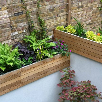 Gravel small town garden Chelsea with a beautiful water feature, acer planters landscaper designers with horizontal timber cladding by Edlis Design Associates.