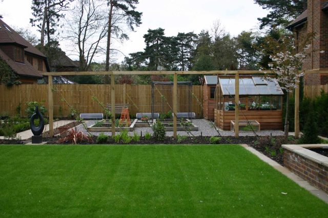 Water Feature Garden design Surrey overgrown woodland space in Surrey with outdoor Hunza lighting designers mature planting, circular paving, cedar pergola.