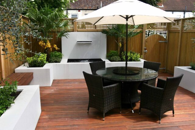 Decking design london elegant walled outdoor entertaining space Wimbledon South West London, lush planting, cozy relaxing outdoor dining area, water feature.