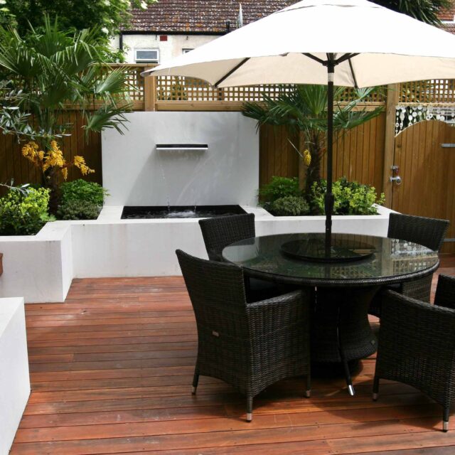 Decking design london elegant walled outdoor entertaining space Wimbledon South West London, lush planting, cozy relaxing outdoor dining area, water feature.