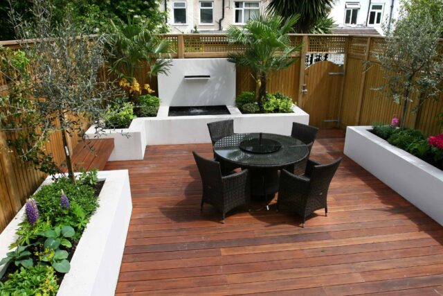 Decking design london elegant walled outdoor entertaining space Wimbledon South West London, lush planting, cozy relaxing outdoor dining area, water feature.