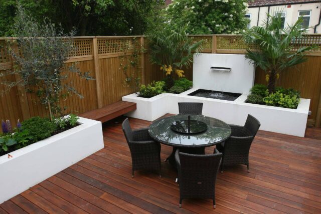 Decking design london elegant walled outdoor entertaining space Wimbledon South West London, lush planting, cozy relaxing outdoor dining area, water feature.