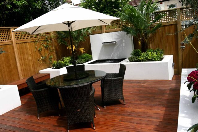 Decking design london elegant walled outdoor entertaining space Wimbledon South West London, lush planting, cozy relaxing outdoor dining area, water feature.