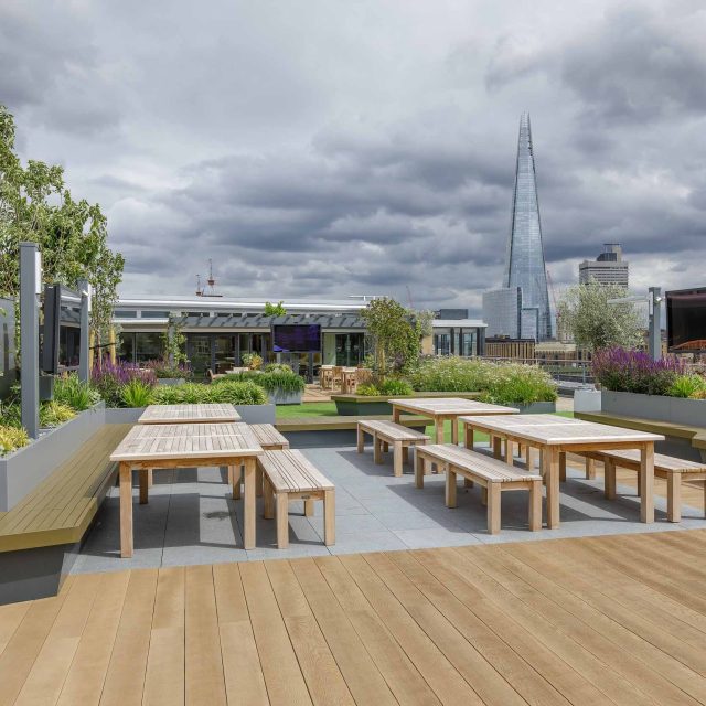 Large Central London commercial roof terrace design, timber benches, planters, artificial lawn, mixed planting outdoor hospitality event space designers London.