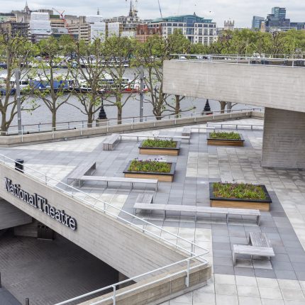 Wooden planters and benches on a brutalist concrete terrace in London.