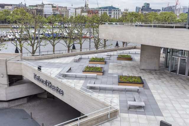 Wooden planters and benches on a brutalist concrete terrace in London.