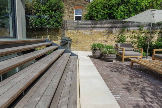 Courtyard Garden Design with an elegant walled space with Yorkstone work Fulham by The Garden Builders, canopy shade for a central lounge planted seating area.