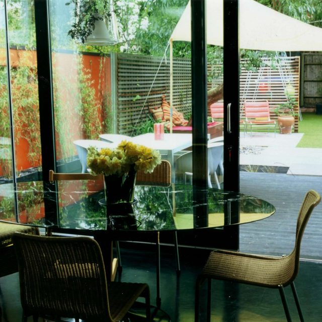 Child friendly synthetic lawn designed as a low-maintenance, contemporary and colourful space, planted raised beds slate terrace hardwood tree seat specialists.