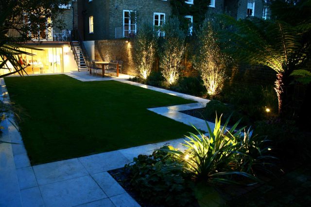 Modern Family Garden in Battersea with patio lighting planting and machined sandstone pathway specialist company stone work, planting herbaceous perennials.