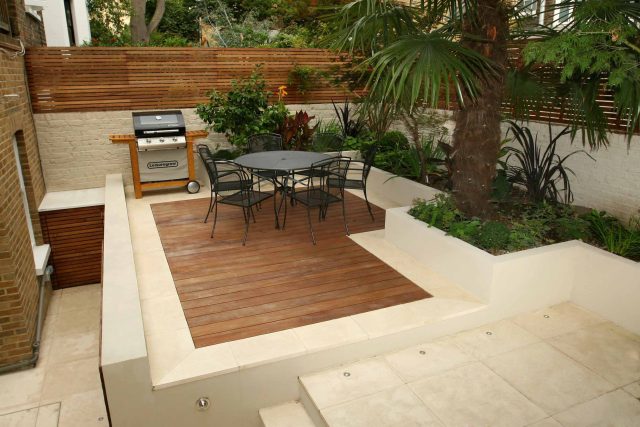 A hardwood deck with a palm tree and limestone paving in a contemporary courtyard.