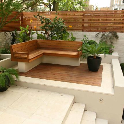 A hardwood deck featuring a slatted bench, limestone paving, and a sago palm.
