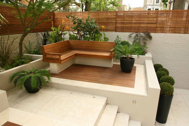A hardwood deck featuring a slatted bench, limestone paving, and a sago palm.