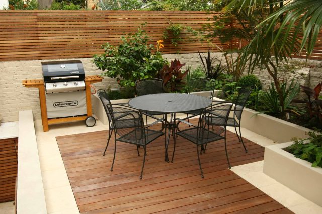 Hardwood decking and a limestone patio area with a slatted fence and dining set.