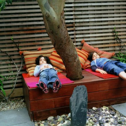 Child friendly synthetic lawn designed as a low-maintenance, contemporary and colourful space, planted raised beds slate terrace hardwood tree seat specialists.