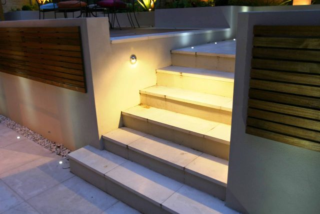 Illuminated limestone steps with LED lighting and slatted wood panels.