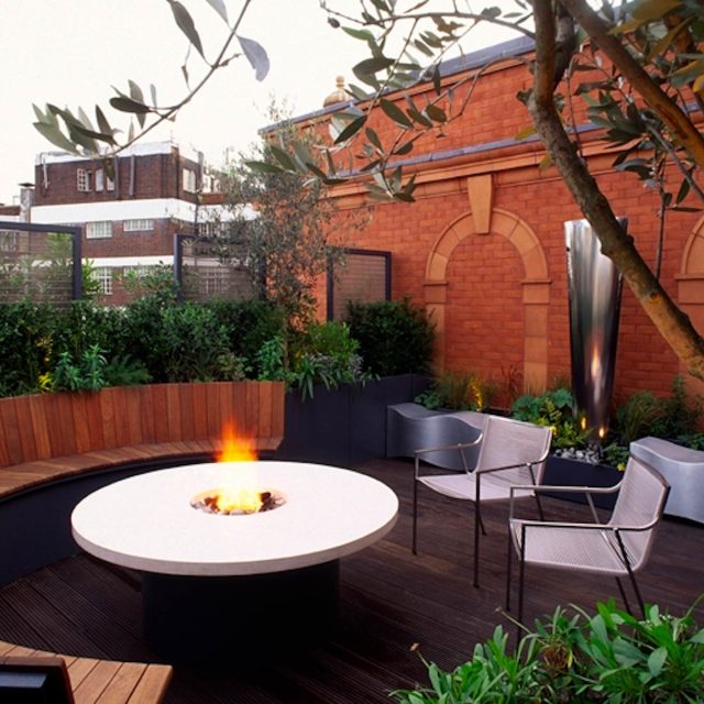 Garden roof terrace Knightsbridge designed with limestone circular table, integrated flambeaux gas unit by Andy Sturgeon, specialist builders, landscapers.