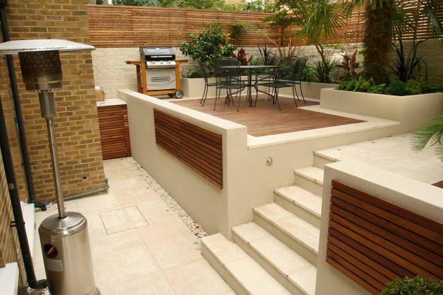 Limestone steps leading to a wooden deck with a contemporary slatted privacy fence.