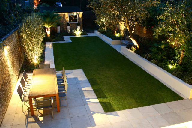 Modern Family Garden in Battersea with patio lighting planting and machined sandstone pathway specialist company stone work, planting herbaceous perennials.