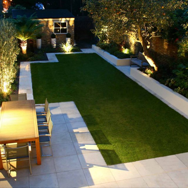 Modern Family Garden in Battersea with patio lighting planting and machined sandstone pathway specialist company stone work, planting herbaceous perennials.