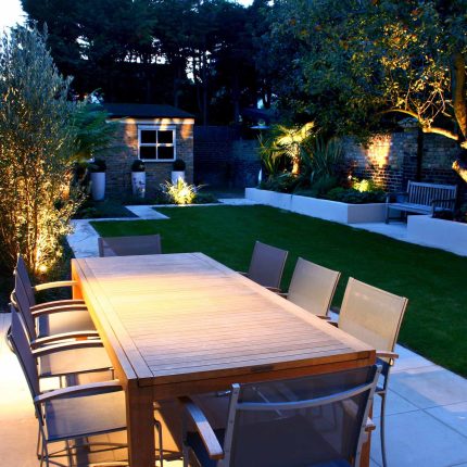 Modern Family Garden in Battersea with patio lighting planting and machined sandstone pathway specialist company stone work, planting herbaceous perennials.