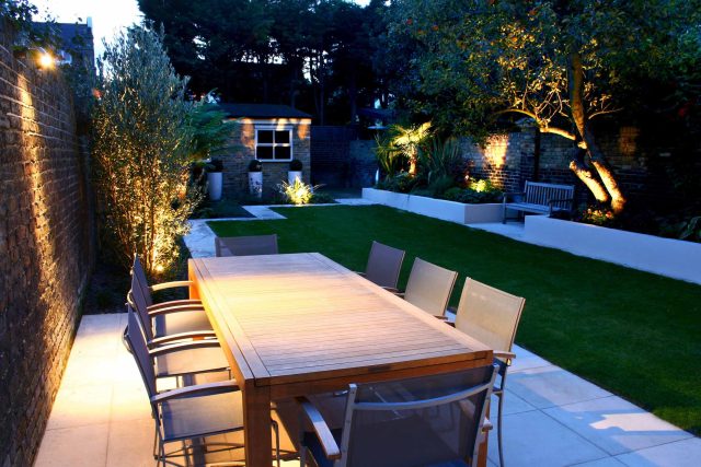 Modern Family Garden in Battersea with patio lighting planting and machined sandstone pathway specialist company stone work, planting herbaceous perennials.