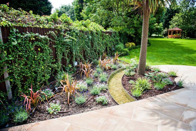 Large suburban garden desigened with York stone dining terrace and timber gazebo in north London, land drainage, lawn, dining terrace, heaters, planting.