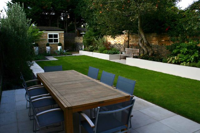 Modern Family Garden in Battersea with patio lighting planting and machined sandstone pathway specialist company stone work, planting herbaceous perennials.