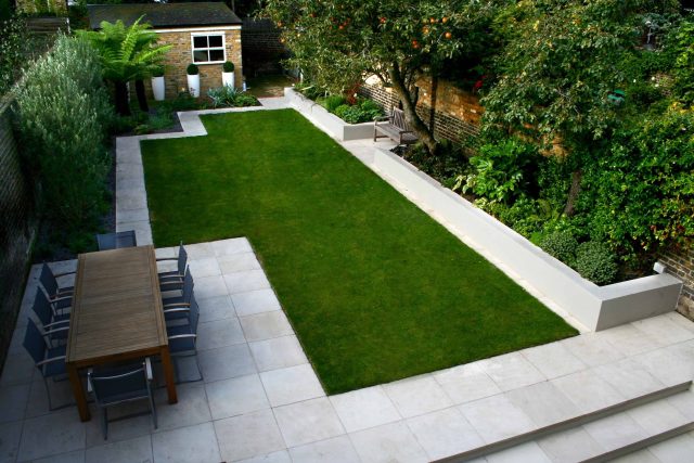 Modern Family Garden in Battersea with patio lighting planting and machined sandstone pathway specialist company stone work, planting herbaceous perennials.