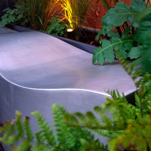 Garden roof terrace Knightsbridge designed with limestone circular table, integrated flambeaux gas unit by Andy Sturgeon, specialist builders, landscapers.
