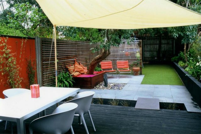Child friendly synthetic lawn designed as a low-maintenance, contemporary and colourful space, planted raised beds slate terrace hardwood tree seat specialists.
