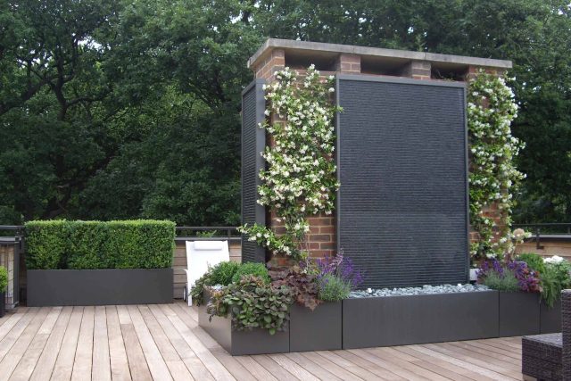 Roof Terrace design in Highgate a bespoke contemporary space with sleek bespoke slate water features steel planters planting olive tree horticulturalist.
