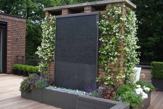 Roof Terrace design in Highgate a bespoke contemporary space with sleek bespoke slate water features steel planters planting olive tree horticulturalist.