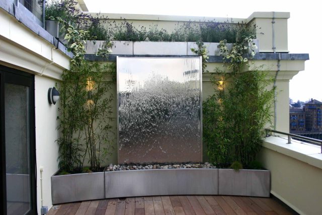 Tower Bridge roof garden terrace design view over the Thames and Bridge in London, huge stainless steel water, robust planting, curved Yew hedge LED lighting.