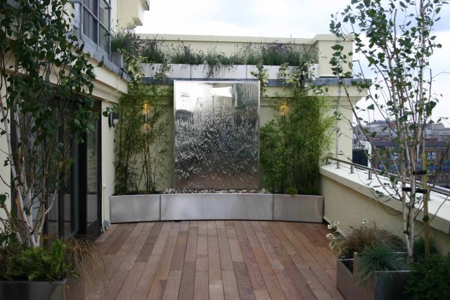 Tower Bridge roof garden terrace design view over the Thames and Bridge in London, huge stainless steel water, robust planting, curved Yew hedge LED lighting.