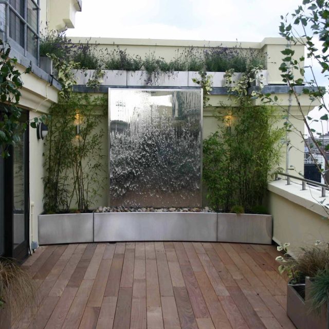 Tower Bridge roof garden terrace design view over the Thames and Bridge in London, huge stainless steel water, robust planting, curved Yew hedge LED lighting.