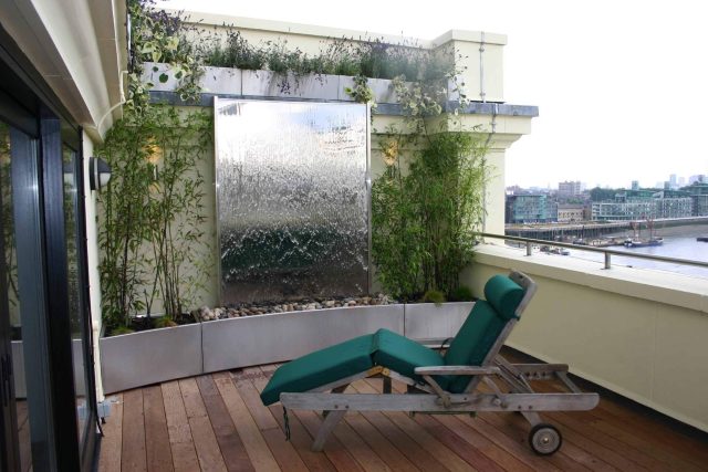 Tower Bridge roof garden terrace design view over the Thames and Bridge in London, huge stainless steel water, robust planting, curved Yew hedge LED lighting.