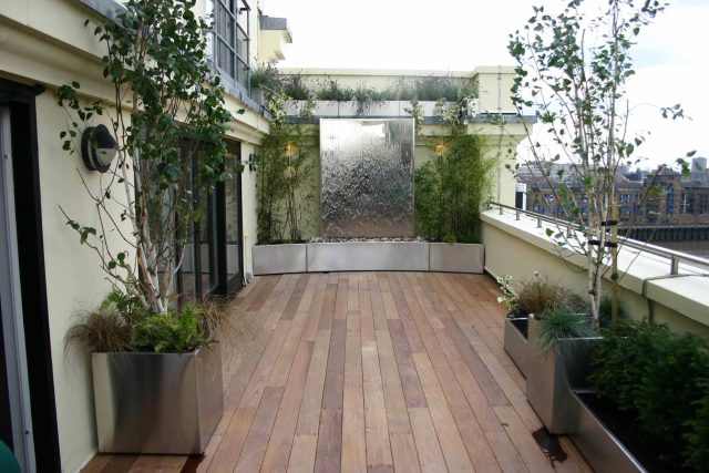 Tower Bridge roof garden terrace design view over the Thames and Bridge in London, huge stainless steel water, robust planting, curved Yew hedge LED lighting.