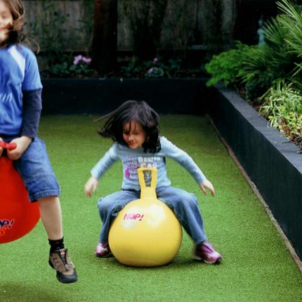 Child friendly synthetic lawn designed as a low-maintenance, contemporary and colourful space, planted raised beds slate terrace hardwood tree seat specialists.