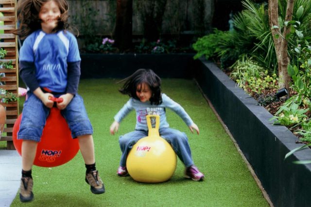 Child friendly synthetic lawn designed as a low-maintenance, contemporary and colourful space, planted raised beds slate terrace hardwood tree seat specialists.